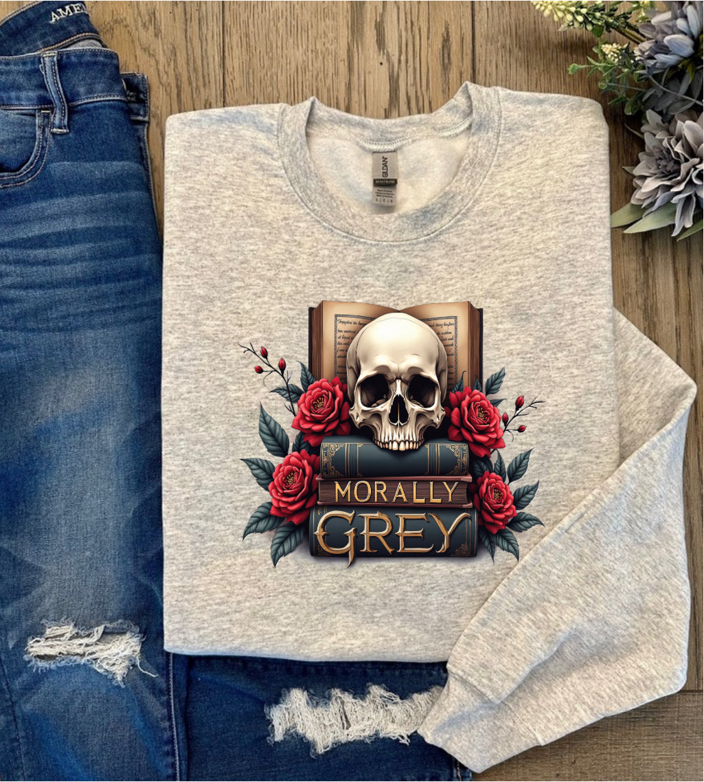 Light gray sweatshirt featuring a gothic bookish design with a skull resting on stacked books surrounded by red roses and the words "Morally Grey"