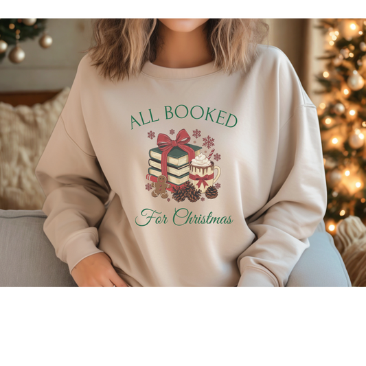 Person wearing a beige sweatshirt with Christmas-themed design and text, sitting in front of a decorated Christmas tree.